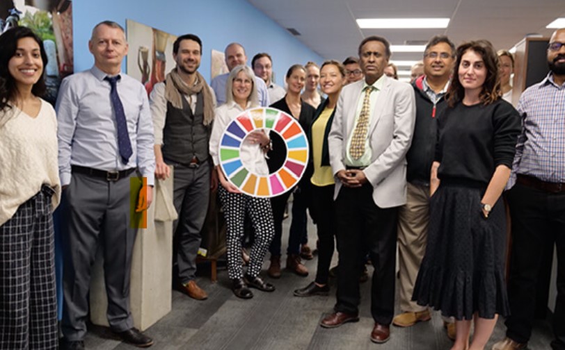 CAWST team standing, with one woman holding the UNSDGs sign